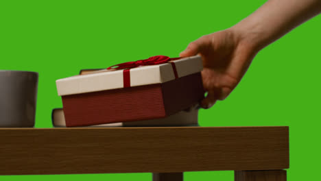 Nahaufnahme-Eines-Mannes,-Der-Ein-Verpacktes-Geschenk-Auf-Einen-Tisch-Legt,-Aufgenommen-Vor-Einem-Greenscreen